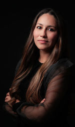 Portrait of smiling young woman against black background