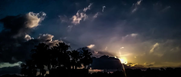 Low angle view of silhouette trees against dramatic sky