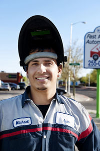 Portrait of mechanic standing against sky