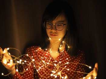 Portrait of woman holding illuminated lighting equipment