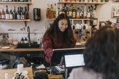Smiling young female owner taking order from customer in cafe