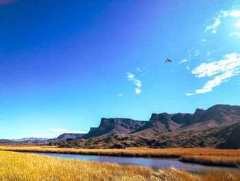 Scenic view of lake and mountains against blue sky