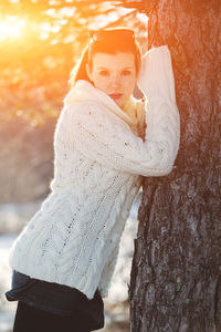 Portrait of young woman standing by tree during winter
