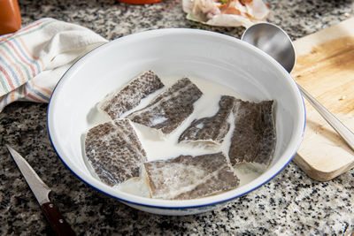 Bowl with cod soaking in milk.