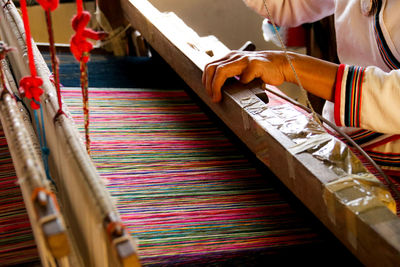 Midsection of person working on loom