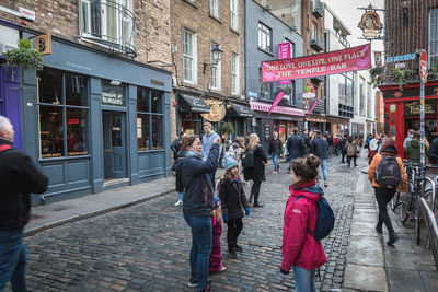 People walking on street amidst buildings in city