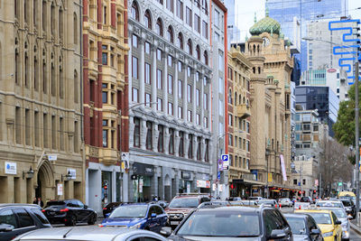 Vehicles on road by buildings in city