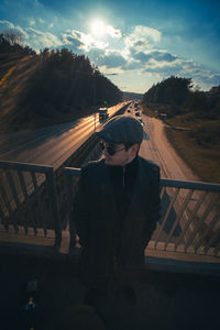 Side view of young man standing against sky during sunset