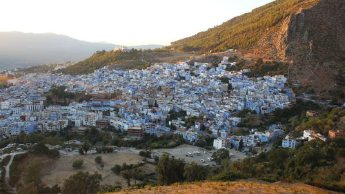 Aerial view of townscape by mountain against sky