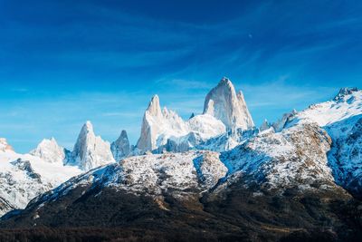 Panoramic view of snowcapped mountains against blue sky