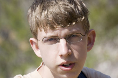 Close-up of teenage boy wearing eyeglasses on sunny day