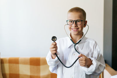 Portrait of a caucasian male child in a doctor's robe with a phonendoscope