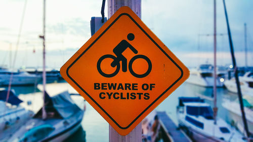 Close-up of beware of cyclists sign at a harbor