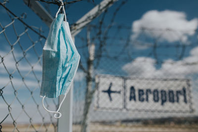 Close-up of blue sign hanging on fence