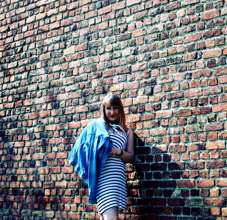 PORTRAIT OF TEENAGE GIRL AGAINST BRICK WALL
