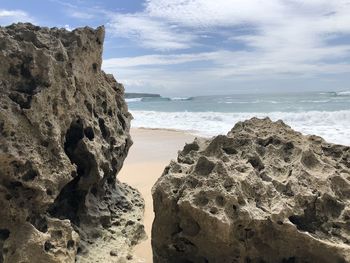 Rock formation on beach against sky