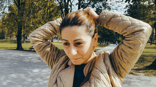 Close-up of mature woman tying hair at park