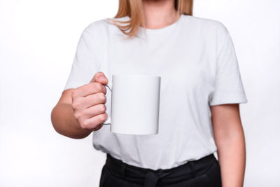 Midsection of a woman drinking water against white background