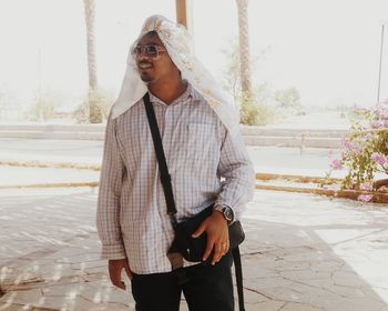 Young man looking away while standing on street