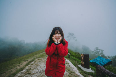 Young woman standing in foggy weather against sky during winter