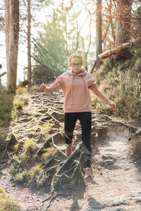 Full length of woman standing by trees in forest