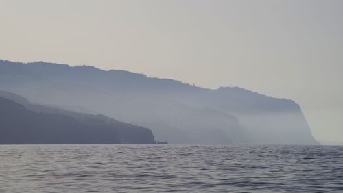 Scenic view of mountains by sea against sky 