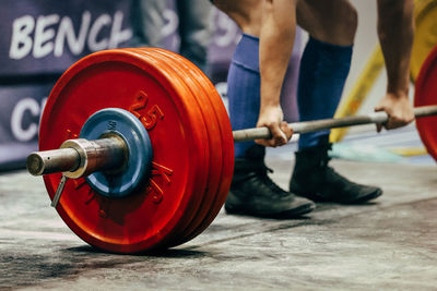 Midsection of man exercising with dumbbell in gym