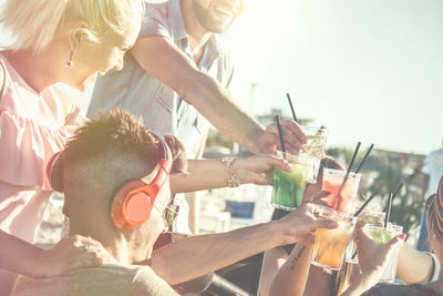 Friends toasting drink at beach during sunny day