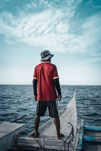 Rear view of man looking at sea against sky