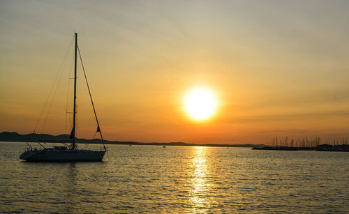 Sailboats in sea against sky during sunset