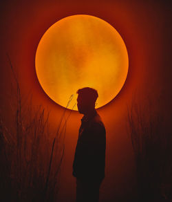 Silhouette man standing against orange sky