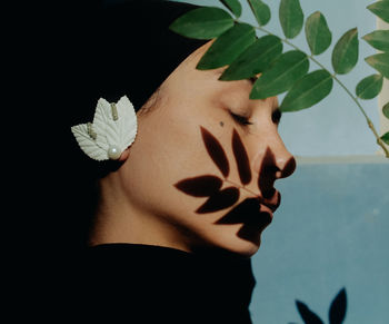 Close-up portrait of woman with hand on plant