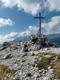 Low angle view of weathered summit cross on rock against mountains and sky, south tyrol, italy 