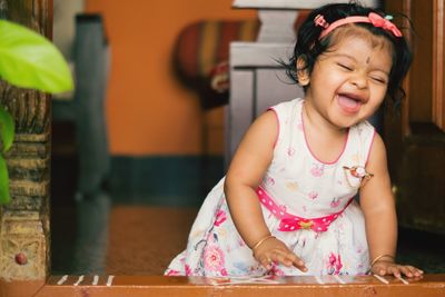 Cute happy baby girl sitting on floor at home