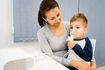 Mother and son with nebulizer on table