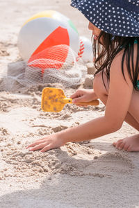 Side view of cute girl in swimwear playing with toys on beach