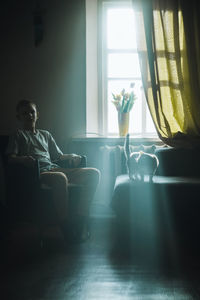 Rear view of woman sitting on bed at home