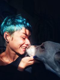 Young woman embracing with dog sitting in darkroom