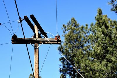 Low angle view of electricity pylon against blue sky