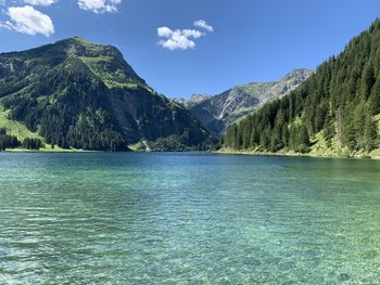 Scenic view of lake and mountains against blue sky