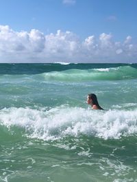 Man surfing in sea against sky