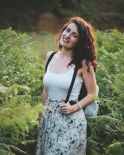 Portrait of smiling young woman standing against plants