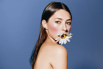 Portrait of beautiful young woman against blue background