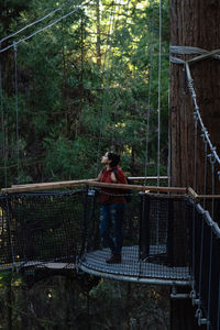 Woman standing by railing in forest