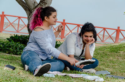 Full length of friends holding mirror frames while sitting at park