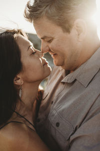 Sunlight on faces of man and woman embracing and touching noses