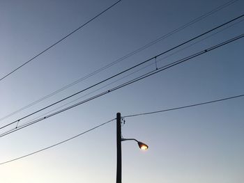Low angle view of street light and cables against sky at dusk