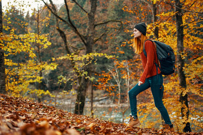 Full length of young woman in autumn leaves in forest