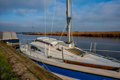 Sailboats moored in sea against sky