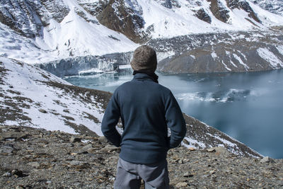 Rear view of man looking at lake against mountains